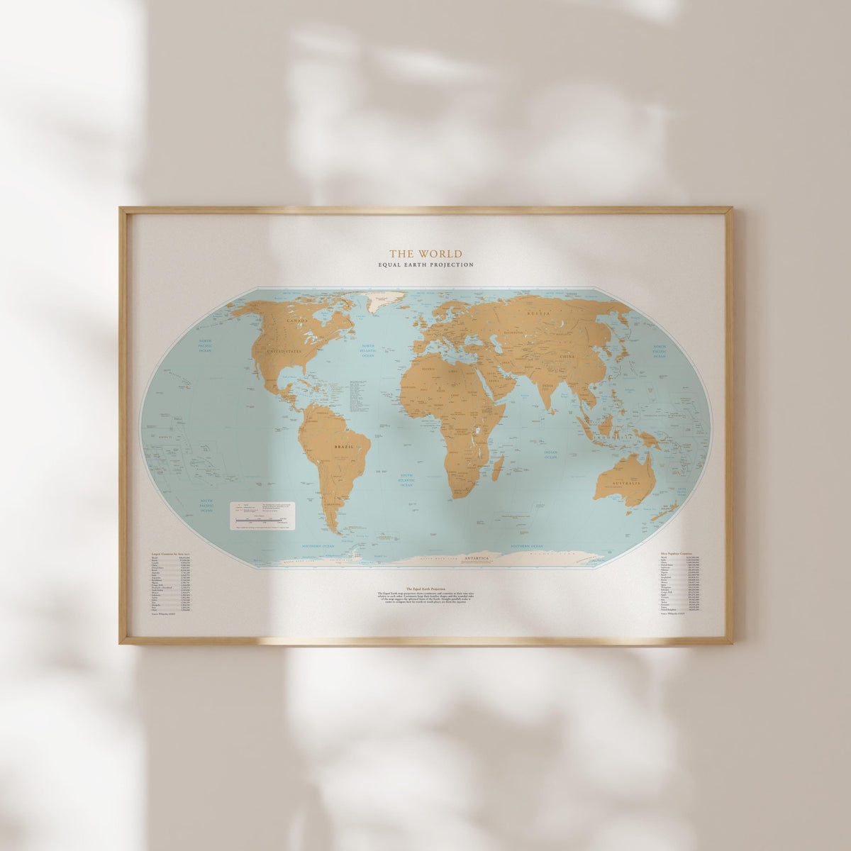 a framed world map with a light blue background and gold borders, hanging on a wall.