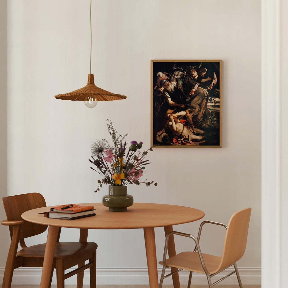 a cozy dining area with a round wooden table, two chairs, a vase of flowers, and a framed painting on the wall.